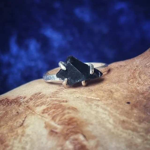 Gros plan sur l'anneau en argent 925 serti de quatre griffes tenant une obsidienne noire brute