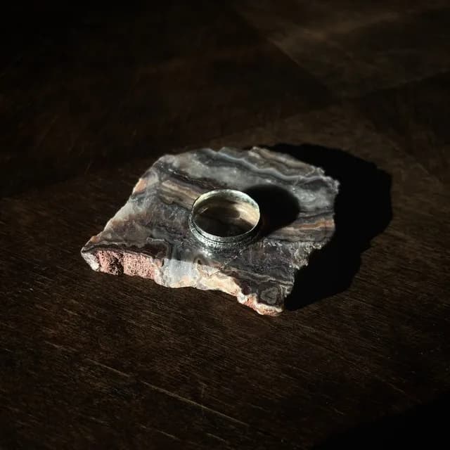 Bague en métal argenté posée sur une tranche de pierre minérale veinée.