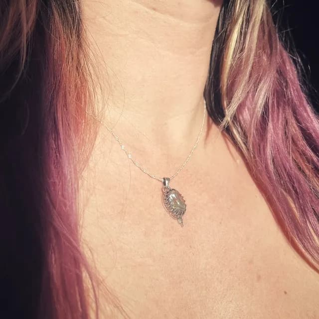 Vue de profil du collier en argent avec son pendentif ovale en abalone porté au cou.