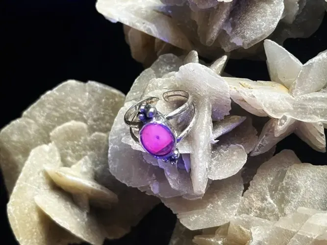 Bague en argent avec pierre luminescente rose fluo sous éclairage UV.