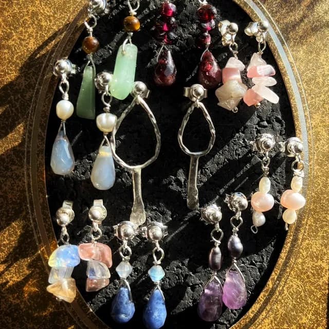 Assortiment de puces d'oreilles pendantes en argent avec diverses perles et pierres naturelles.