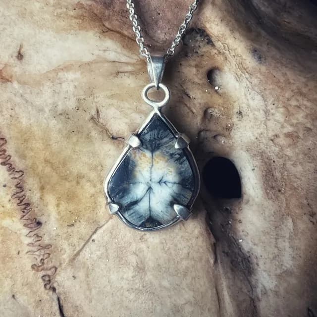 Pendentif en argent en forme de goutte serti d'une pierre d'andalousite aux motifs naturels gris et beiges.
