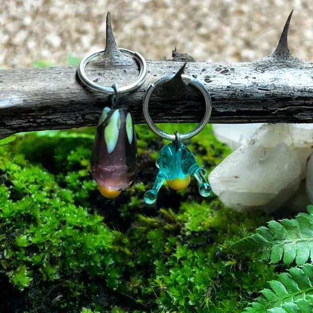 Créoles à perles en verre sculpté pendantes, suspendues à une branche épineuse.