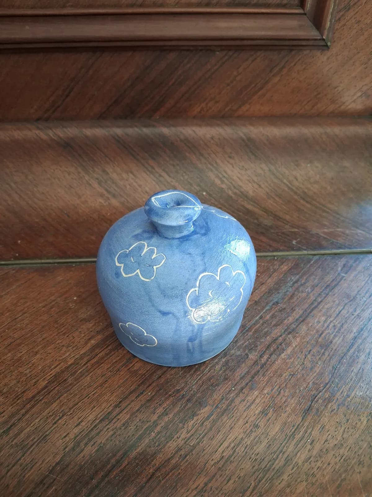 Arrosoir-main en céramique bleu orné de motifs de nuages, posé sur un meuble en bois.