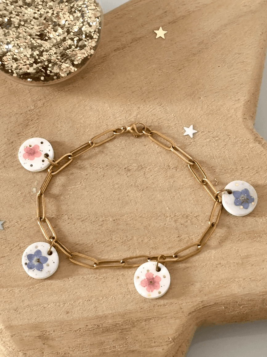 Bracelet chaîne dorée avec quatre médaillons blancs ornés de fleurs de myosotis bleues et roses