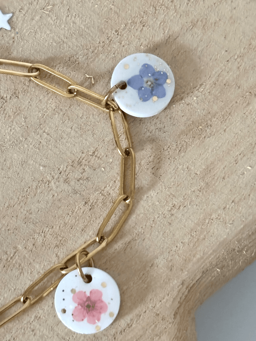 Détail de la chaîne dorée à maillons allongés et des pampilles rondes à fleurs et paillettes