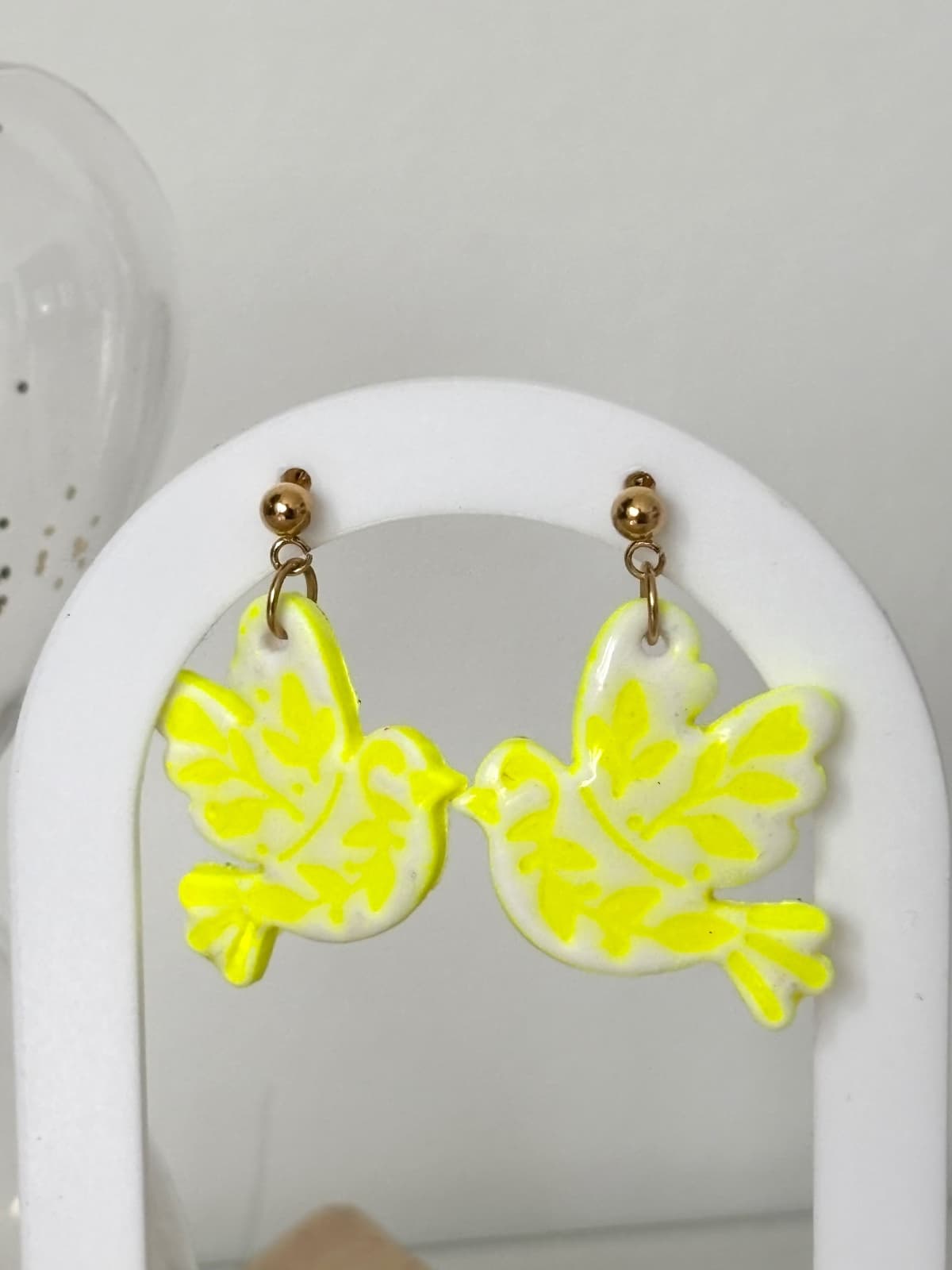 Boucles d'oreilles légères en silhouette d'oiseau blanc et jaune néon aux finitions dorées.