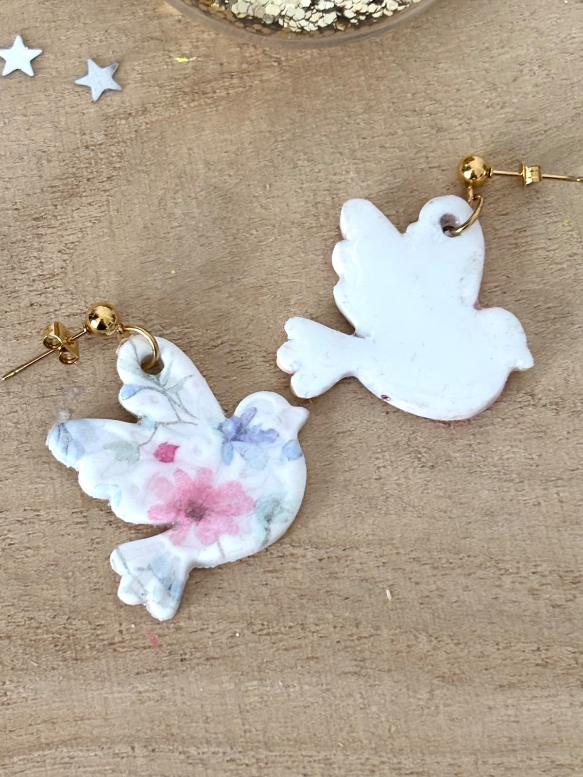 Recto et verso des boucles oiseaux montrant la face fleurie et l'envers blanc uni sur fond bois