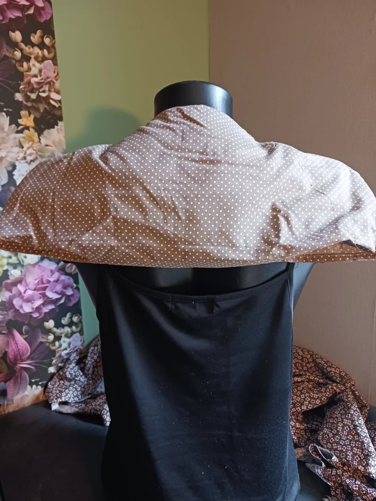 Vue arrière de la bouillotte beige à pois couvrant la nuque et les trapèzes sur un mannequin.