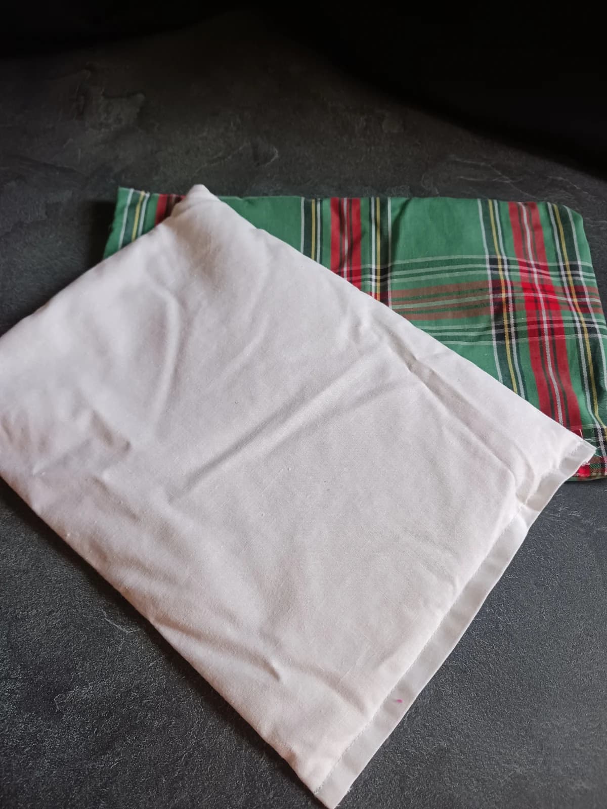 Poche intérieure blanche posée sur la housse de coussin tartan vert et rouge.