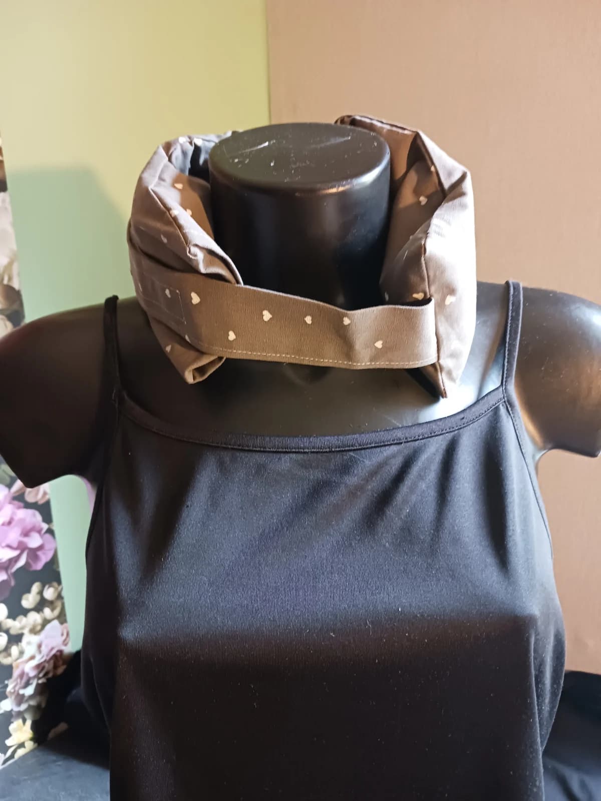 Bouillotte tour de cou en tissu taupe à motifs cœurs portée sur un mannequin de face