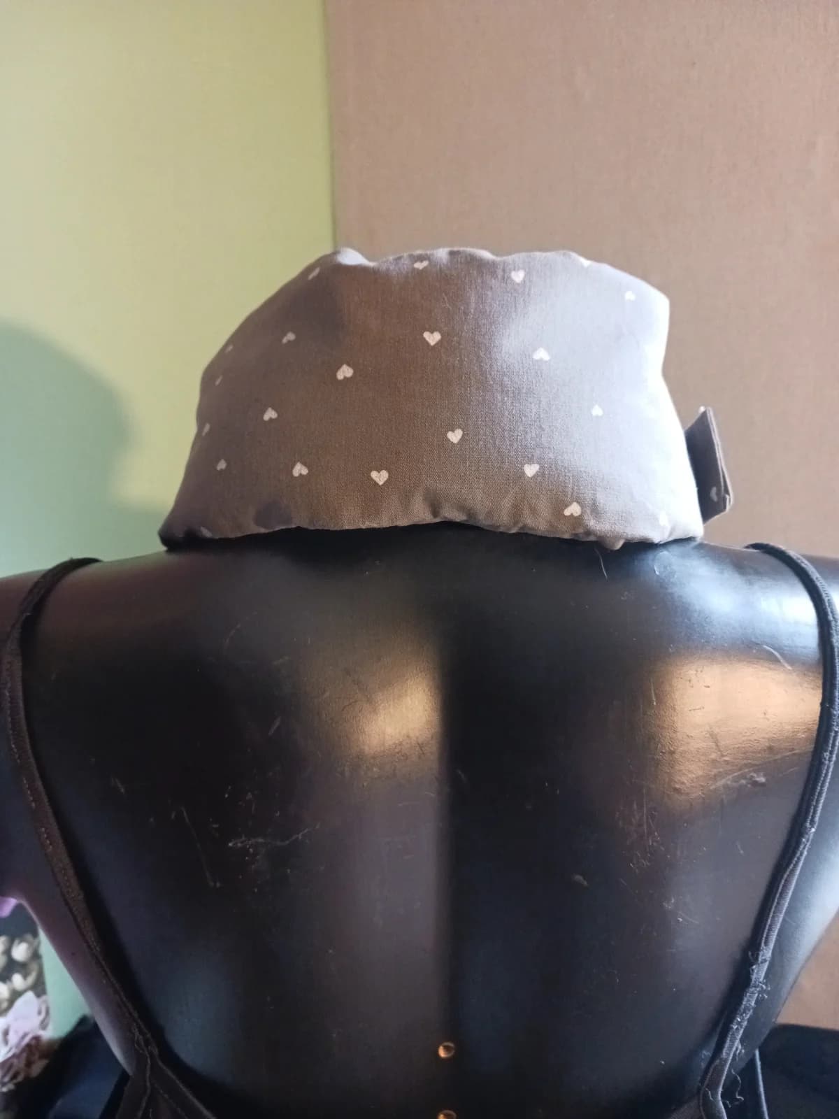 Vue arrière du tour de cou en tissu taupe à cœurs blancs positionné sur la nuque