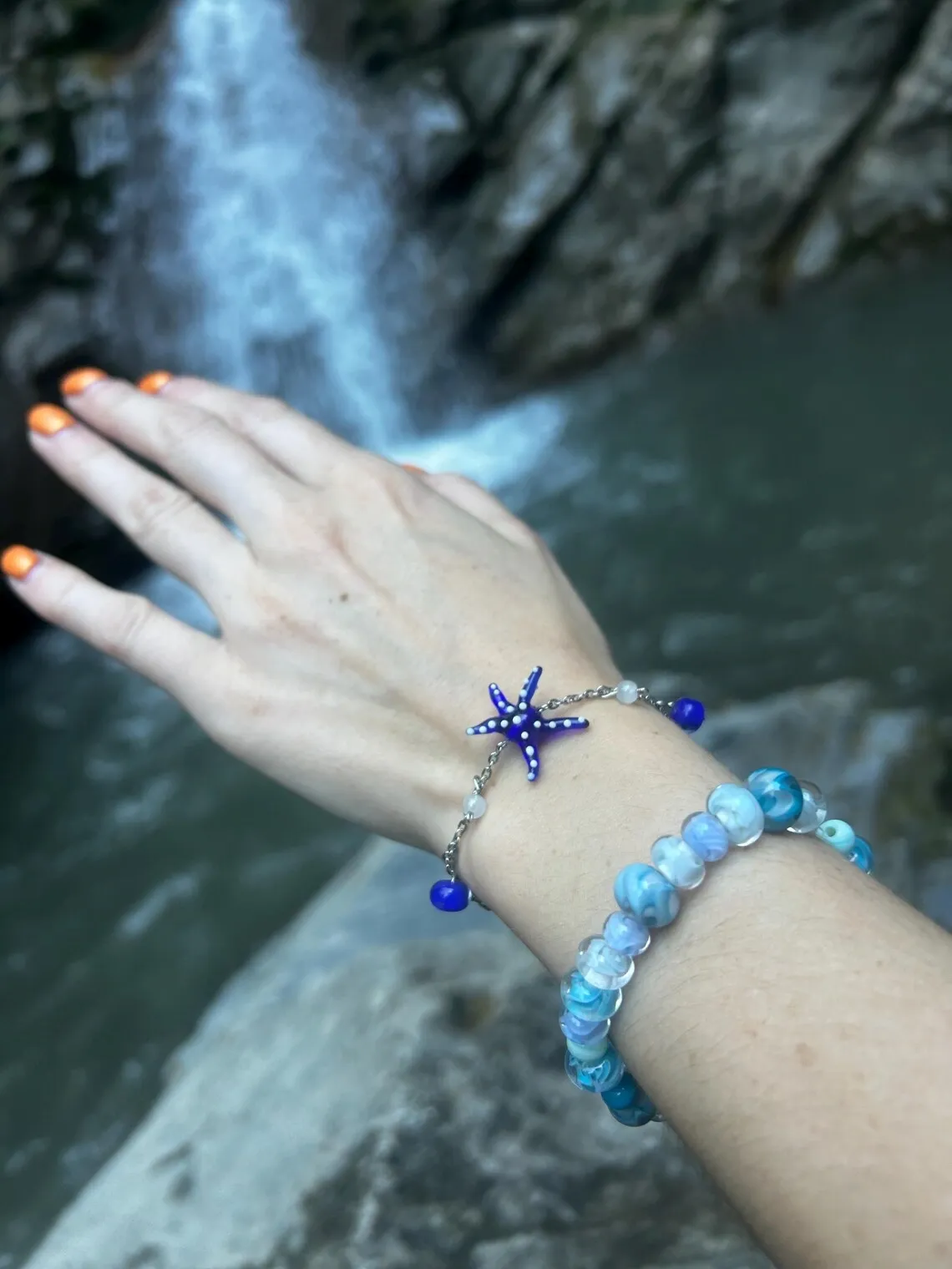 Femme portant le bracelet étoile de mer bleue assorti au collier près d'une cascade