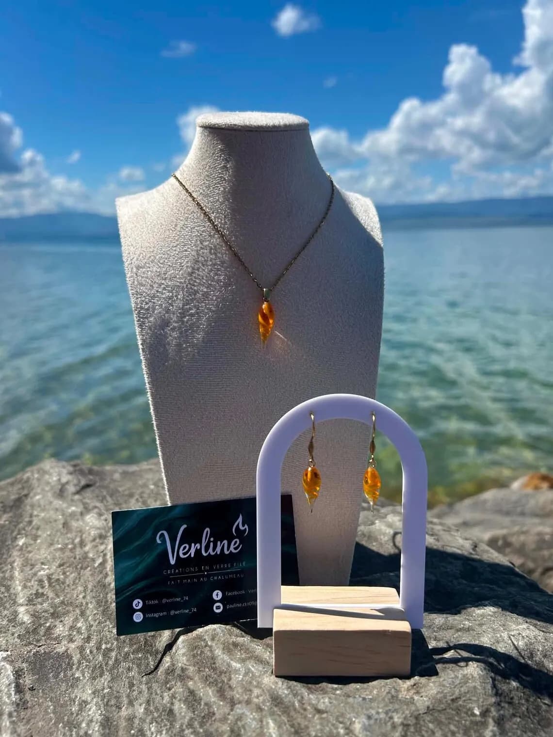 Collier et boucles d'oreilles en verre filé orange en forme de gouttes présentés en extérieur.