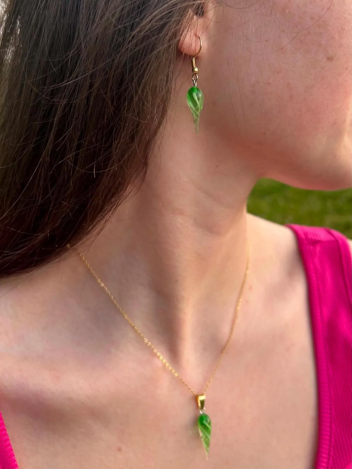Boucle d'oreille pendante verte torsadée portée avec un collier assorti