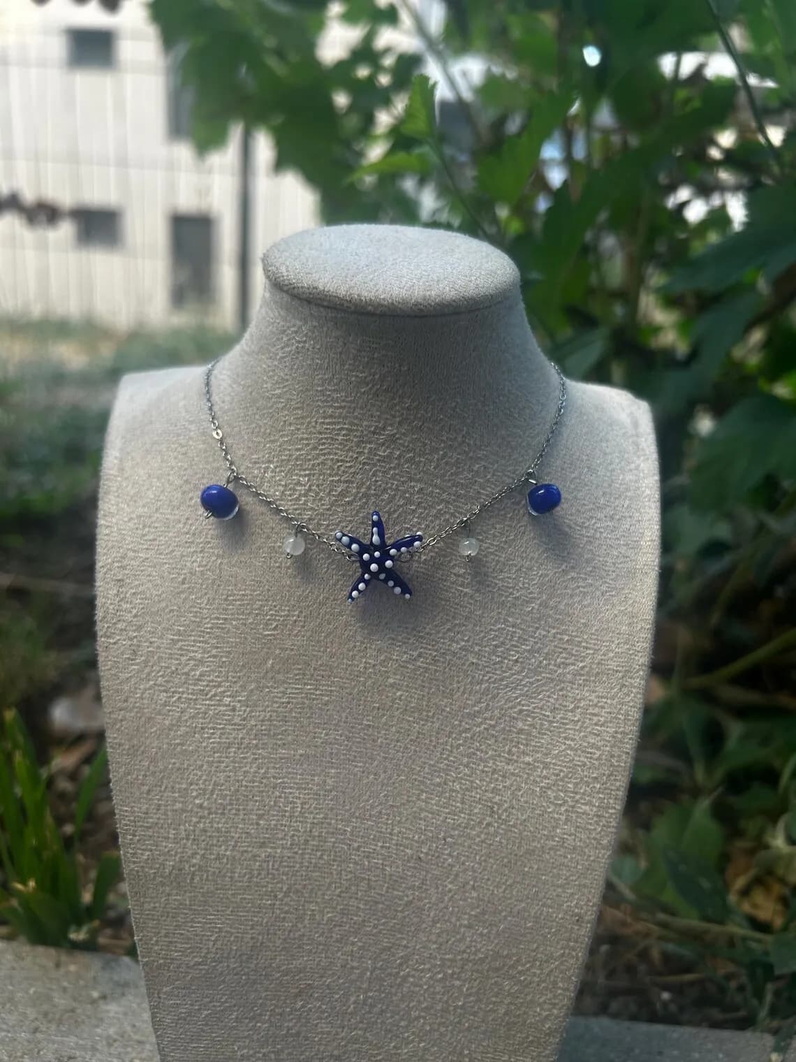 Collier ras-de-cou orné d'une étoile de mer bleue et de petites perles porté par une femme