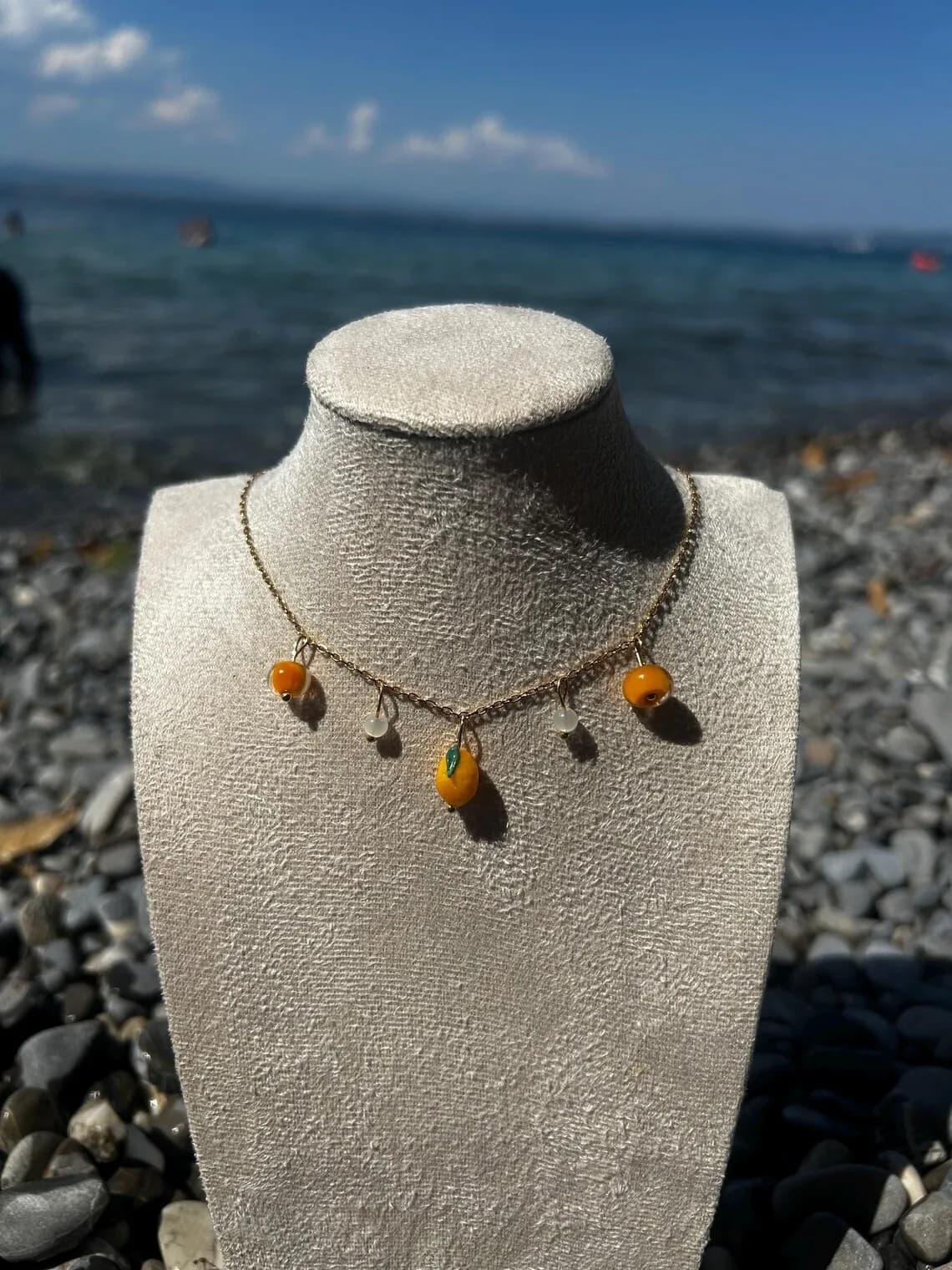 Collier fin à pampilles citrons jaunes porté au cou avec une boucle d'oreille assortie