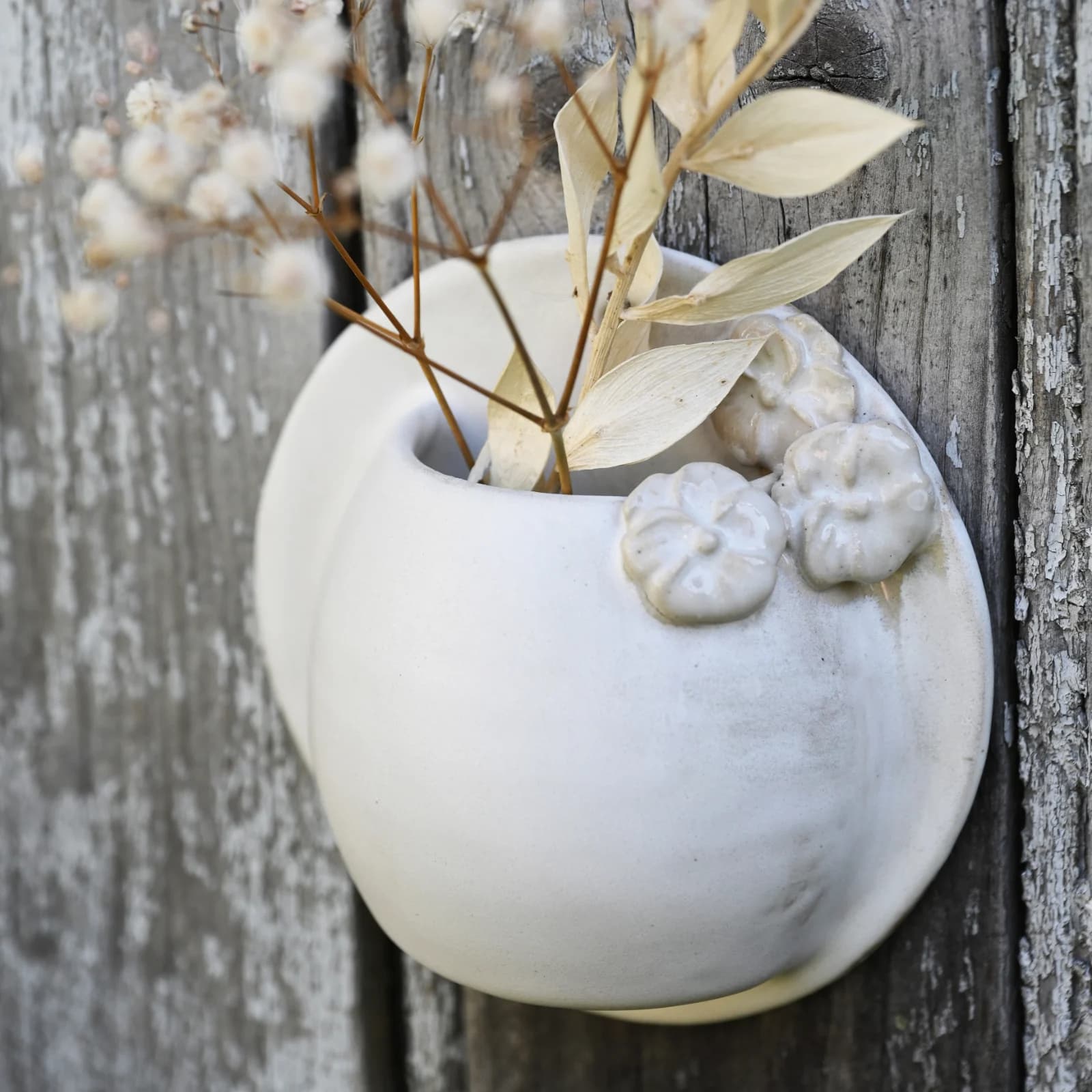 Vase mural en céramique blanche orné de fleurs modelées