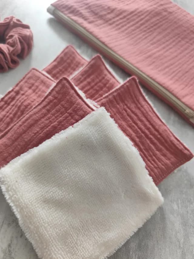 Gros plan sur les lingettes lavables roses et blanches disposées devant la trousse et le chouchou.