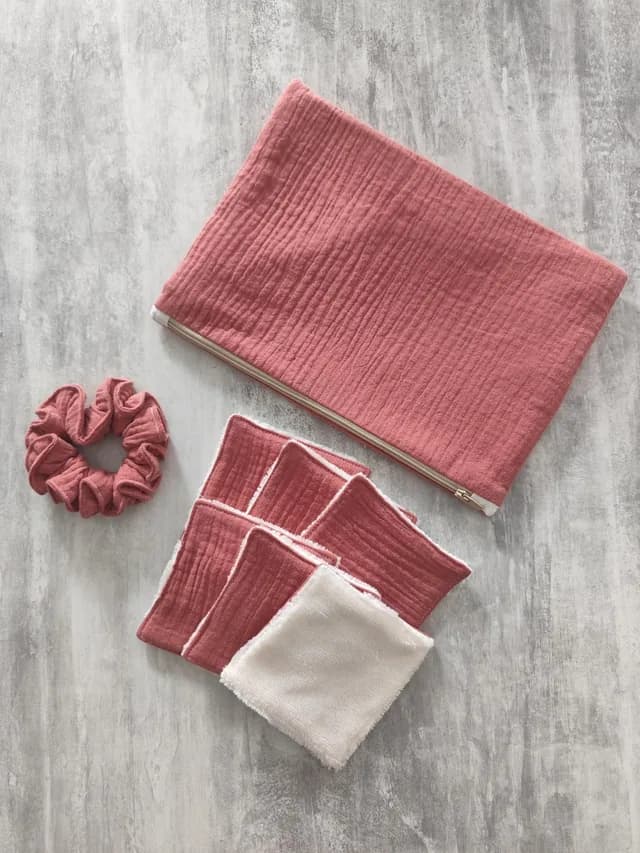 Pochette zippée rose, chouchou assorti et lingettes lavables avec face en tissu éponge blanc.
