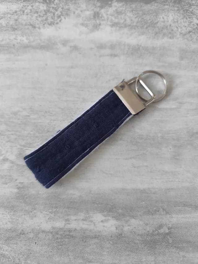 Porte-clé en tissu texturé bleu marine avec attache et anneau en métal argenté