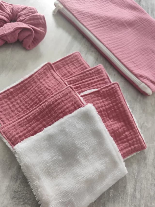 Gros plan sur les lingettes lavables roses et blanches avec pochette zippée et chouchou en arrière-plan.