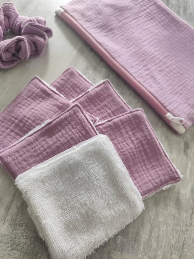 Détail de lingettes lavables carrées avec face éponge blanche et tissu rose texturé, pochette et chouchou.