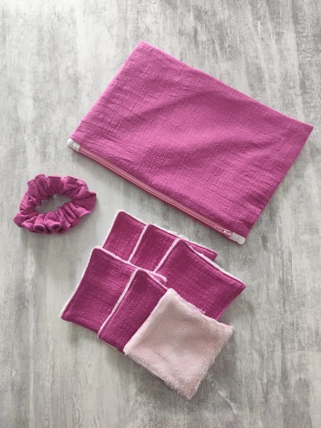 Kit rose avec pochette zippée, chouchou et six lingettes lavables carrées posées à plat.