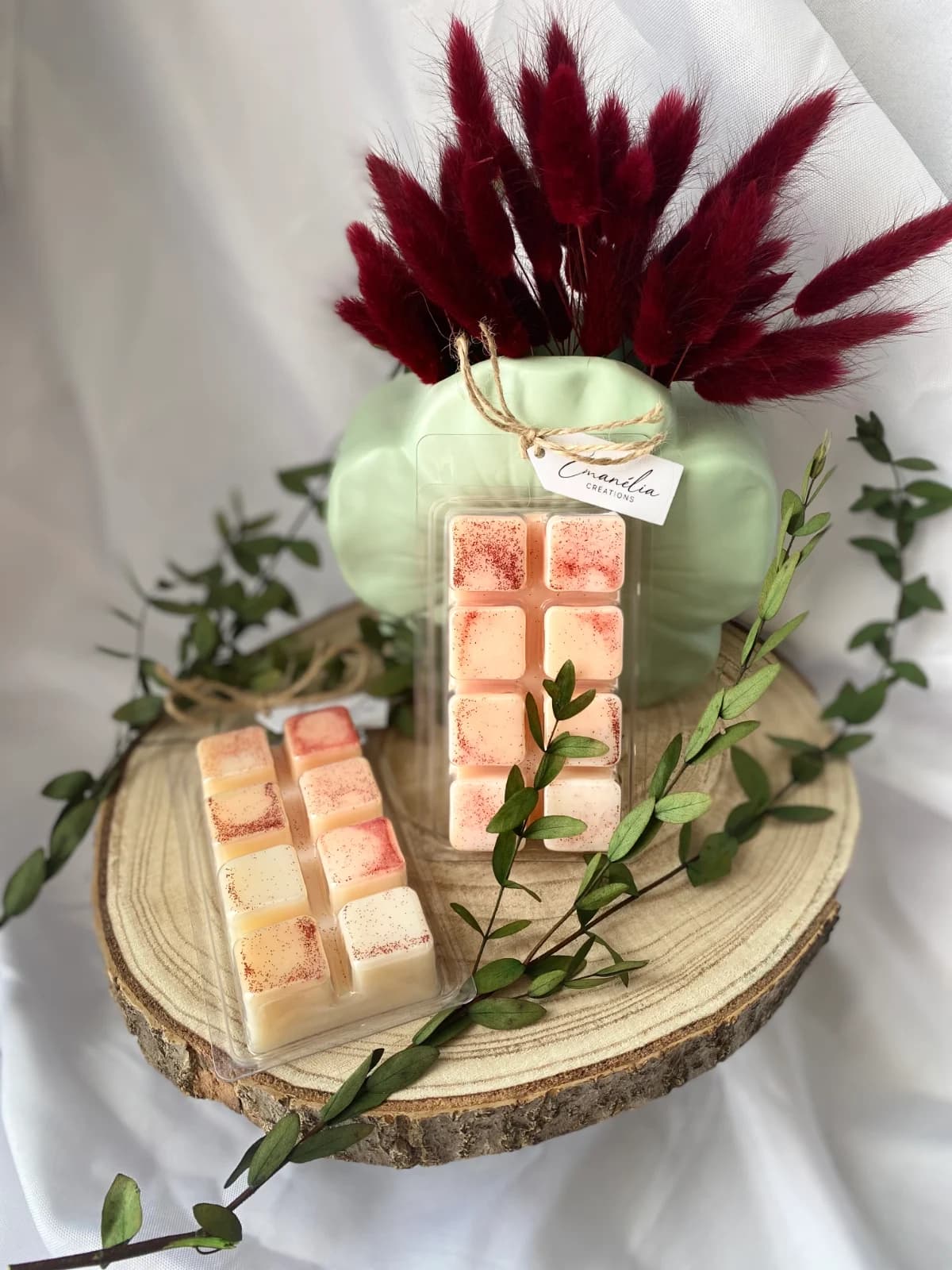 Tablettes de cire parfumée à 8 carrés pailletés posées sur un rondin de bois décoré.