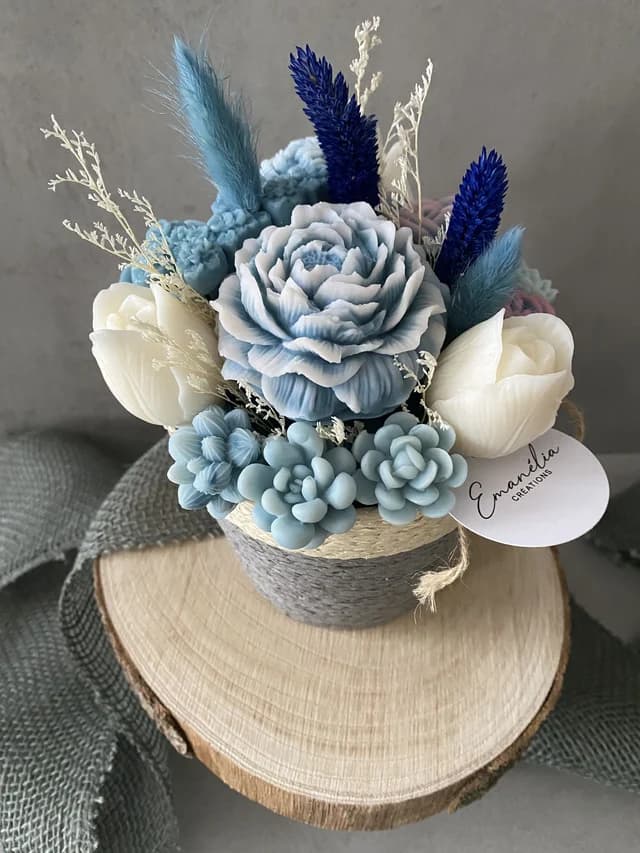 Bouquet de fleurs parfumées bleu pastel et blanc dans un pot gris posé sur un rondin de bois