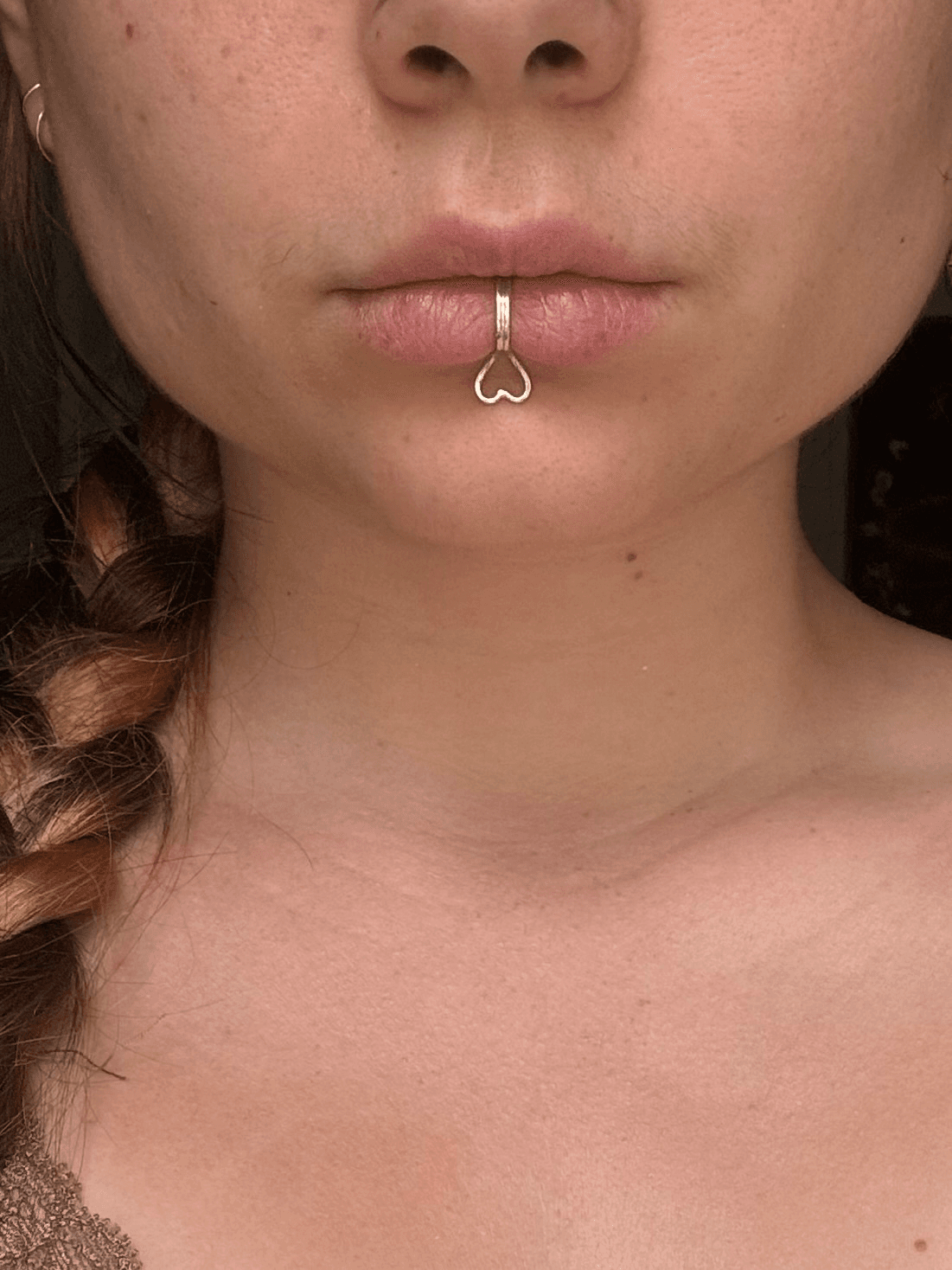 Gros plan de face sur un bijou de bouche en argent orné d'un cœur ajouré sur la lèvre inférieure.